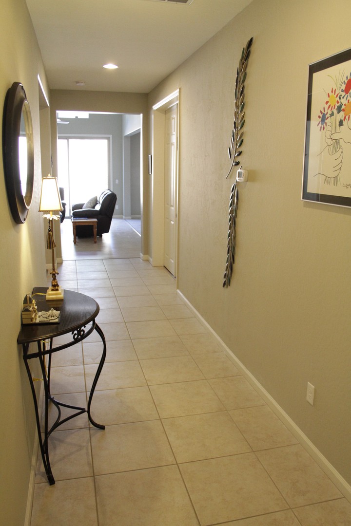 A well-lit hallway with wall decorations and a small side table, leading to a living area.