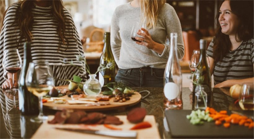 A casual gathering with friends enjoying wine and a charcuterie board in the kitchen.