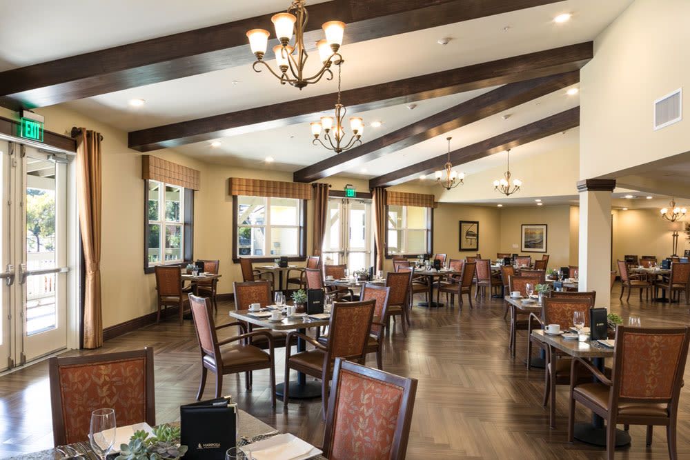 Elegant dining area with wooden flooring and large windows.