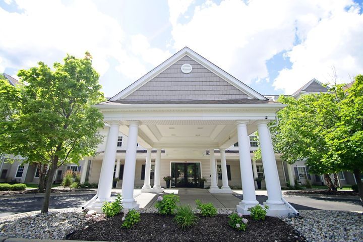A stately building entrance with large white columns and manicured landscaping.