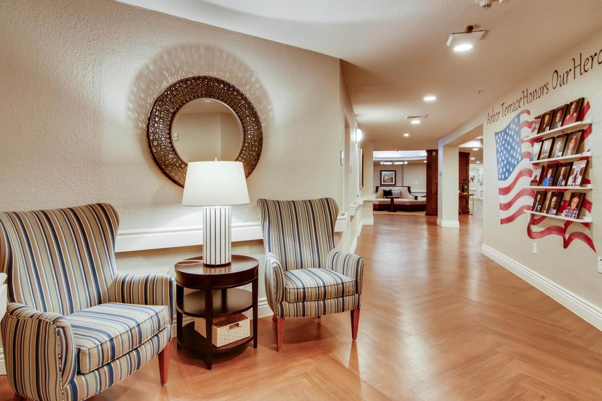 A cozy waiting area with two striped chairs and a lamp in a well-lit hallway.