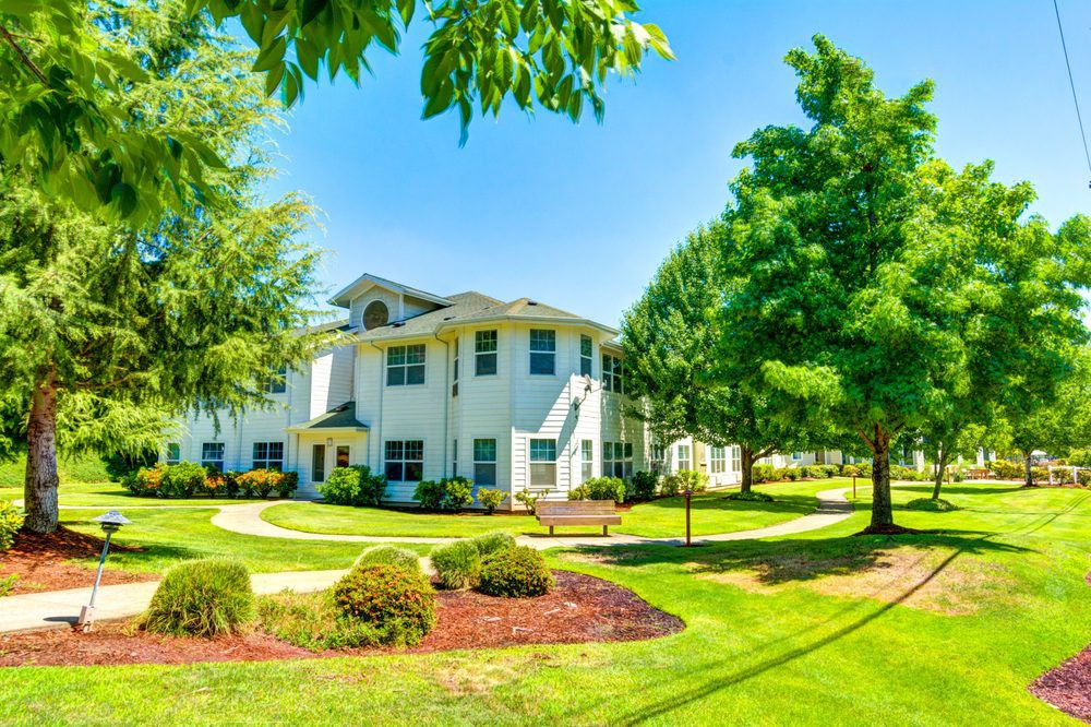 A sunny day highlighting a well-maintained apartment building surrounded by lush greenery and landscaped gardens.