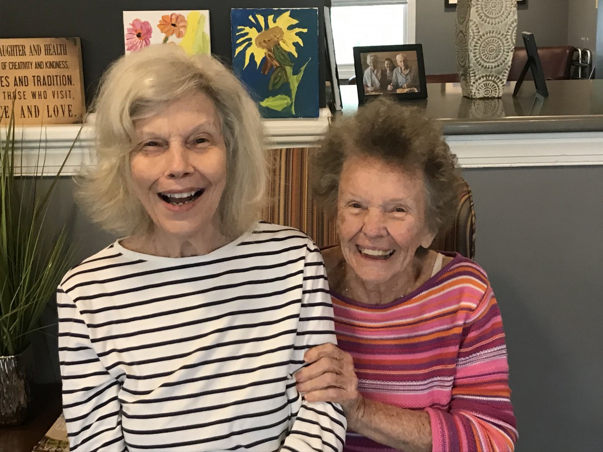Two elderly women smiling together indoors.