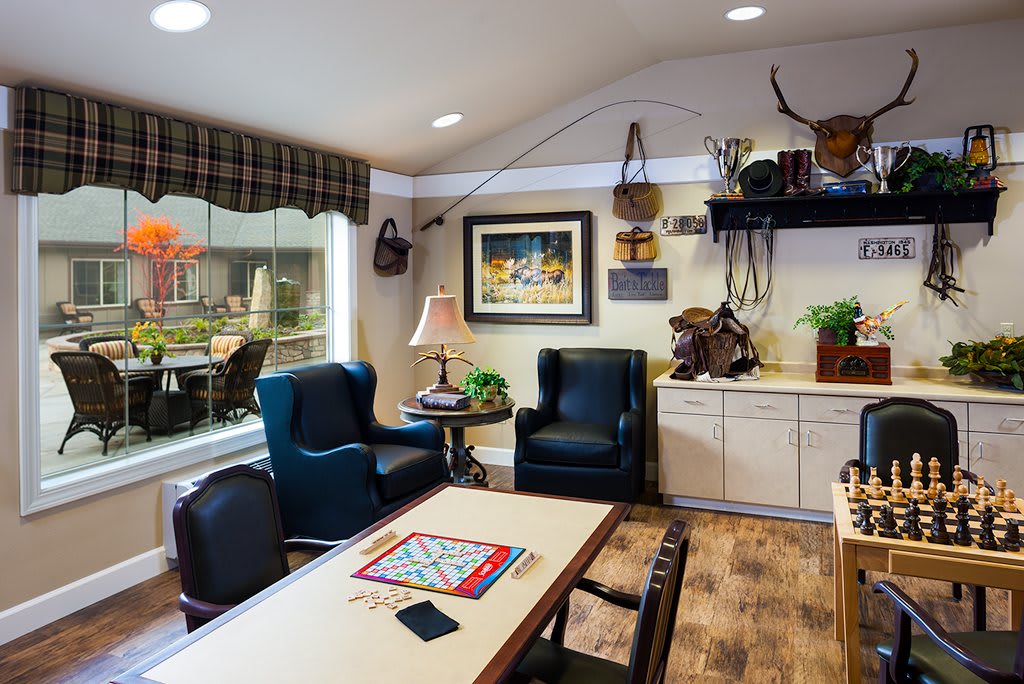 A cozy living room featuring comfortable chairs, a table with a board game, and decorative elements, offering a relaxing atmosphere.