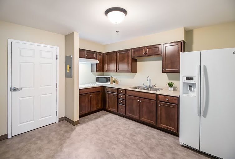 A modern kitchen with wooden cabinets, a refrigerator, and a microwave.