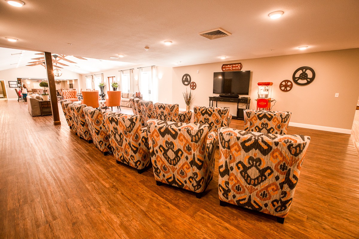 A cozy lounge area with patterned chairs facing a TV for group entertainment.