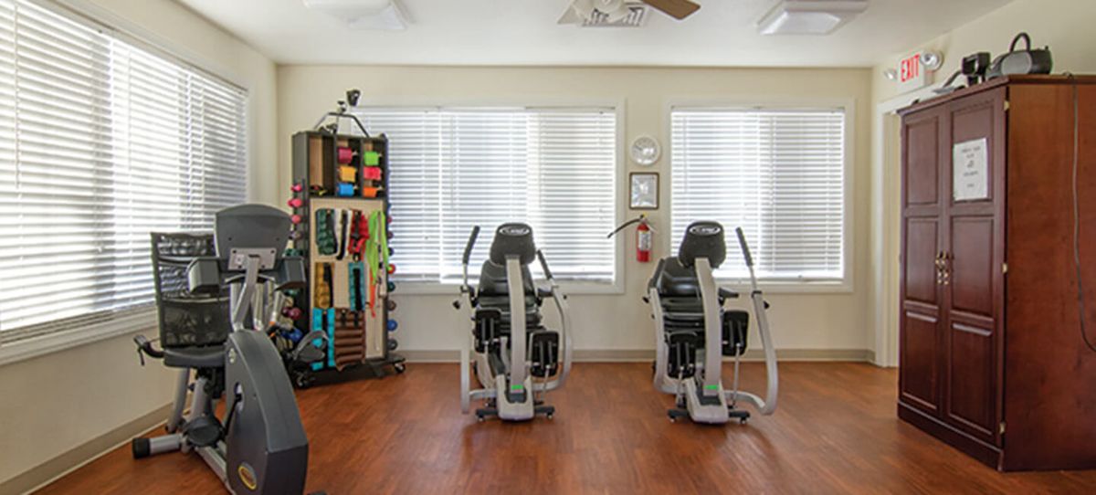 A fitness room with exercise machines and therapy supplies.