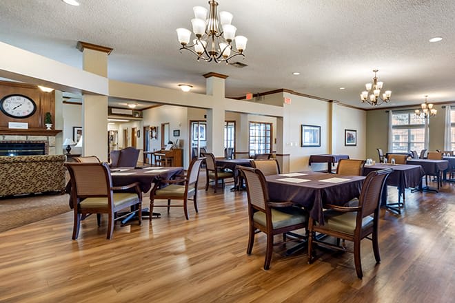 A spacious dining room with elegant chandeliers and polished wood flooring.