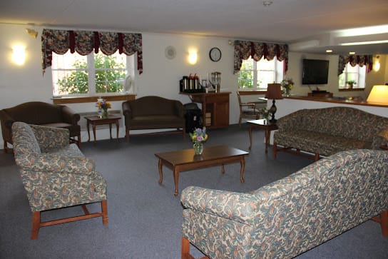A cozy living room with multiple sofas, tables, and windows letting in natural light.