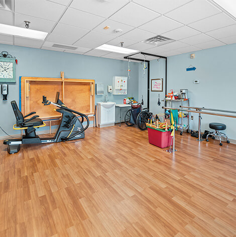 A spacious physical therapy room equipped with various exercise machines and rehabilitation tools.