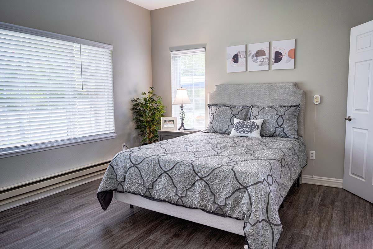 A modern bedroom with stylish decor, featuring a neatly made bed, wall art, and natural light streaming through the windows.