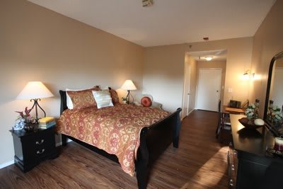 A cozy bedroom with a decorative bed, warm lighting, and wooden flooring.