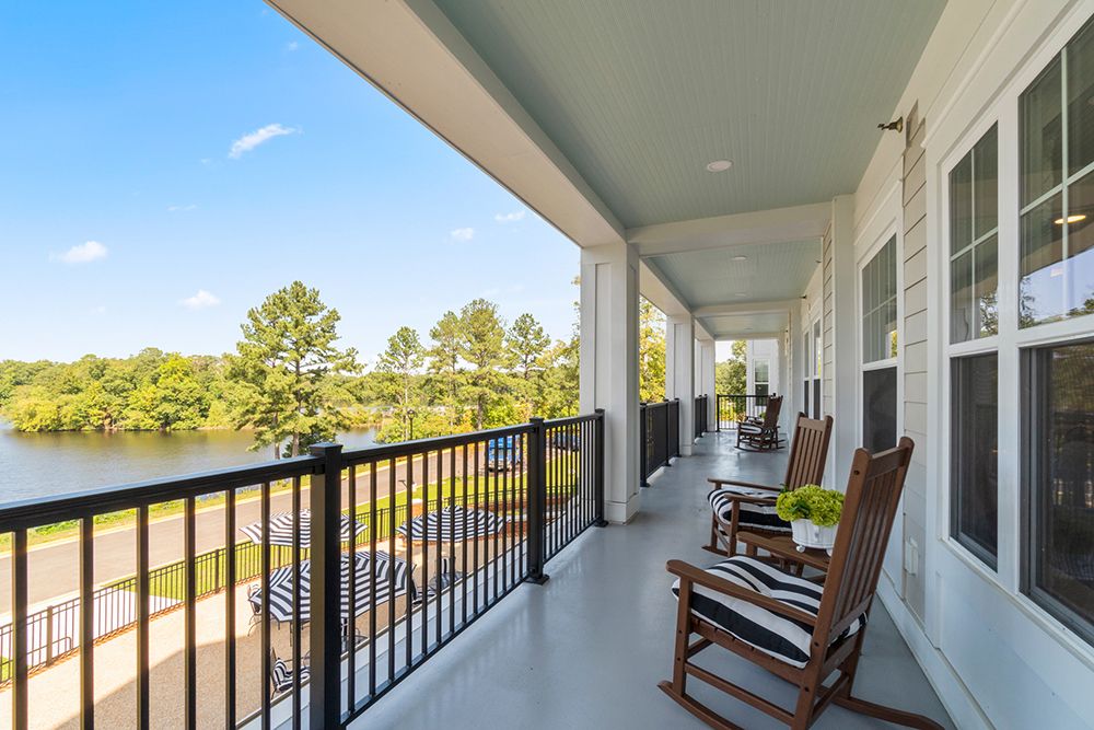 A spacious porch with rocking chairs overlooking a scenic view of trees and a clear sky.