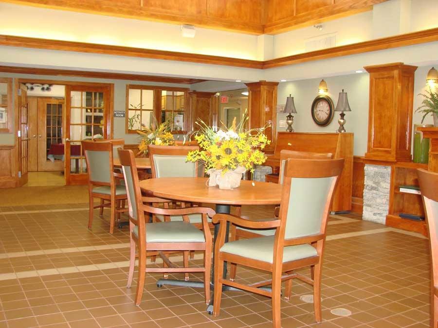 A cozy dining area featuring wooden furniture and a table centerpiece with bright yellow flowers.
