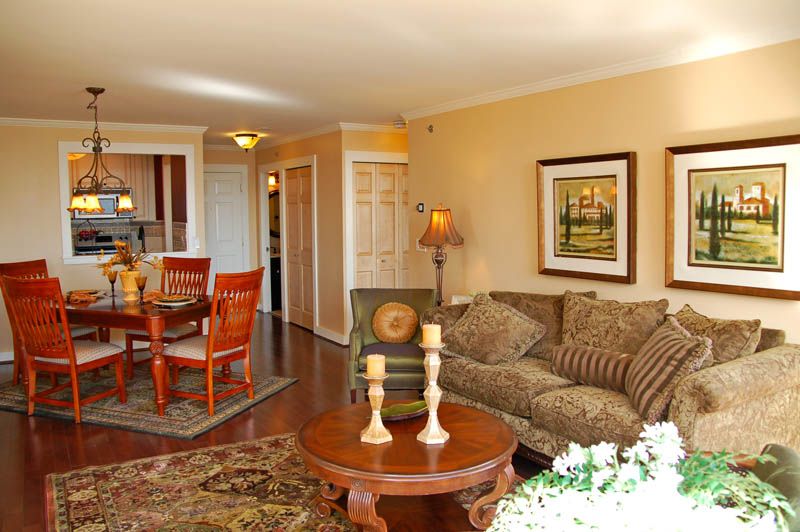 A cozy living room with a sofa, wooden coffee table, dining area, and decorative artwork on the wall.