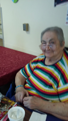 An elderly woman smiling while sitting at a table.
