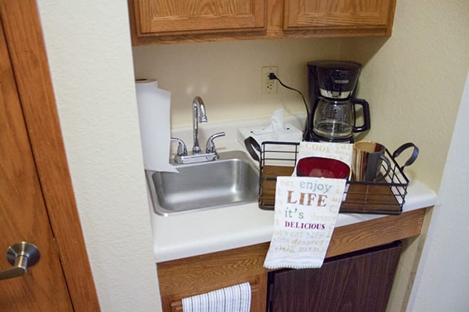 A small kitchen area with a sink, coffee maker, and other essentials.
