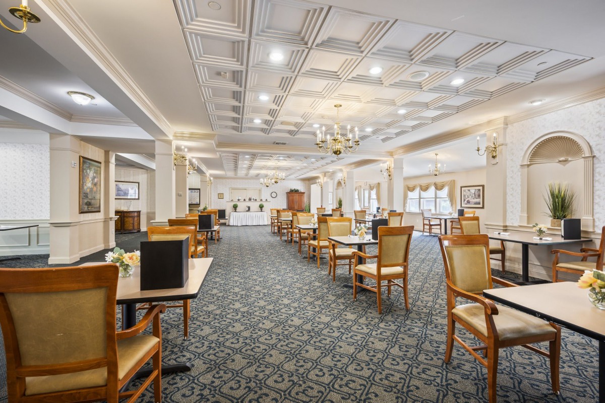 An elegant dining room interior with neatly arranged tables and a chandelier.