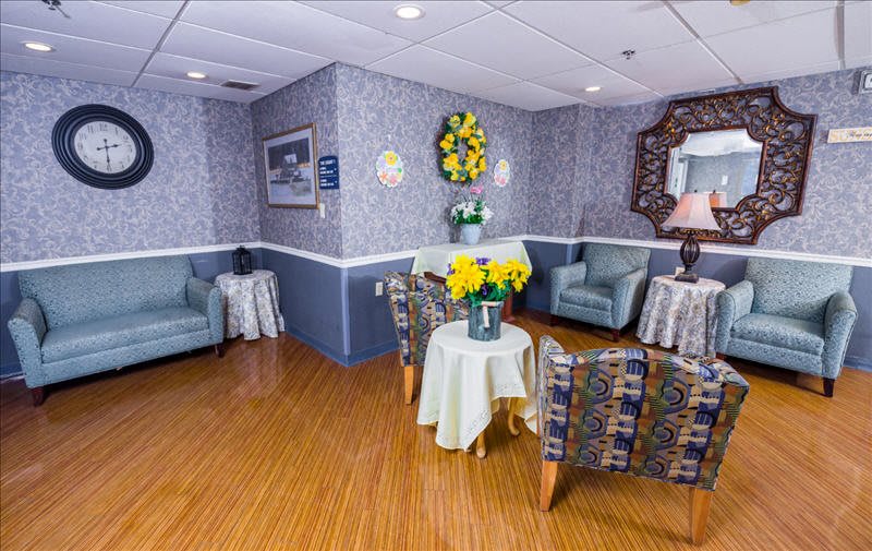 A cozy waiting area with comfortable chairs, a table adorned with flowers, and decorative elements on the walls.