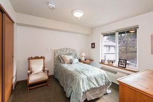 A cozy bedroom with a single bed, armchair, and a window allowing natural light.