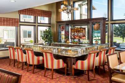 A stylish bar area featuring a marble countertop, striped upholstered chairs, and elegant wooden accents.