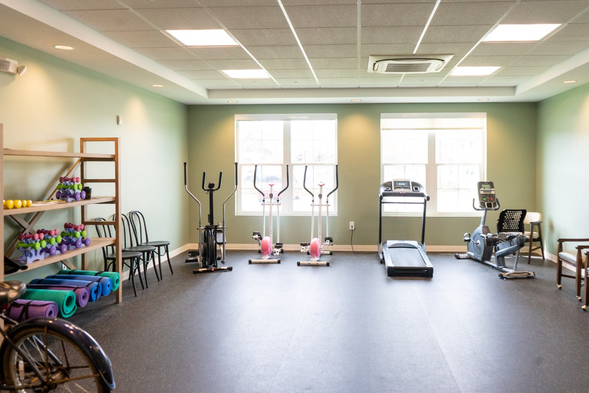 A bright and spacious gym with various exercise equipment.