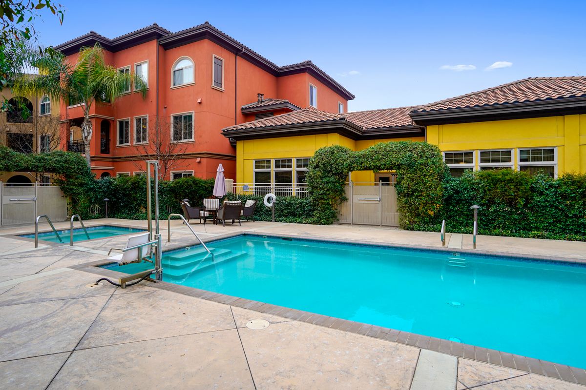 A residential apartment complex with a swimming pool and outdoor seating area.
