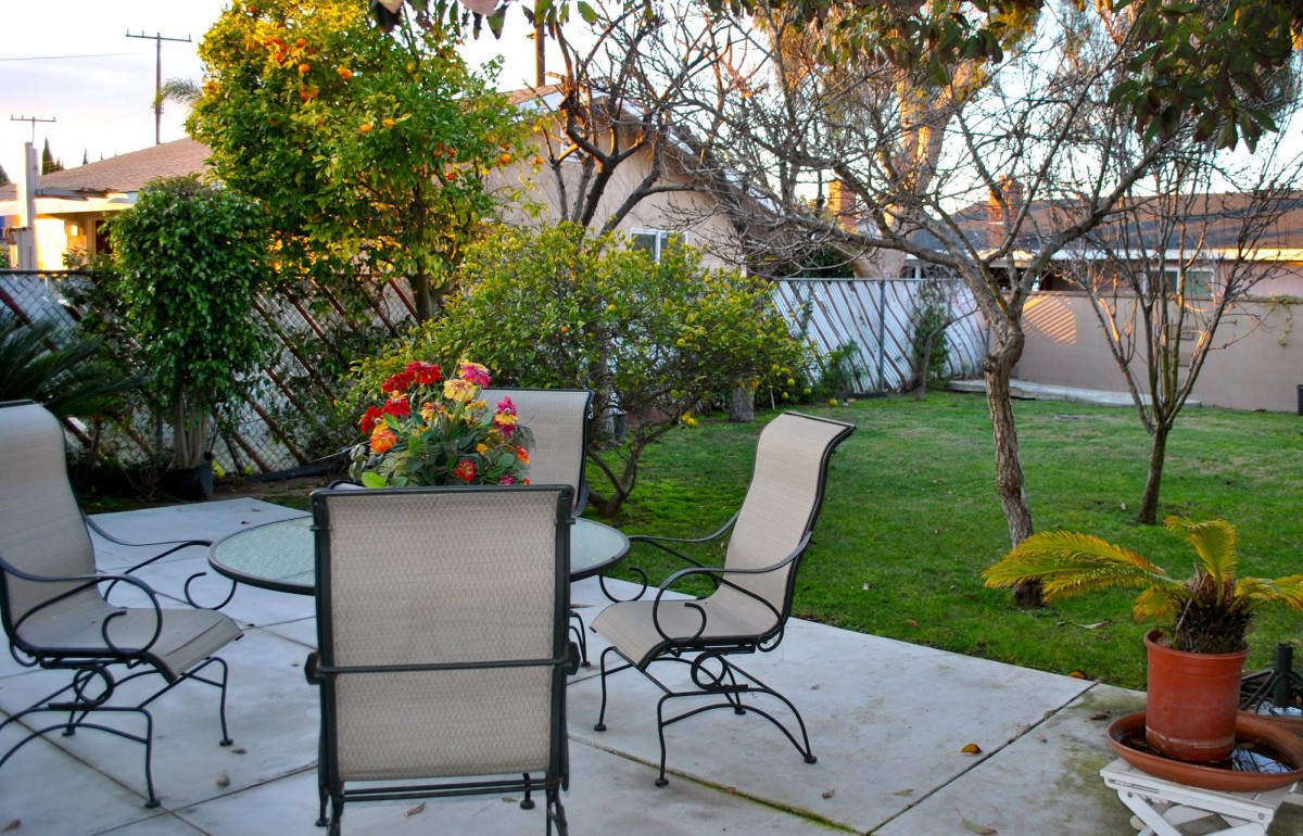 A tranquil patio with a table and chairs surrounded by lush greenery.
