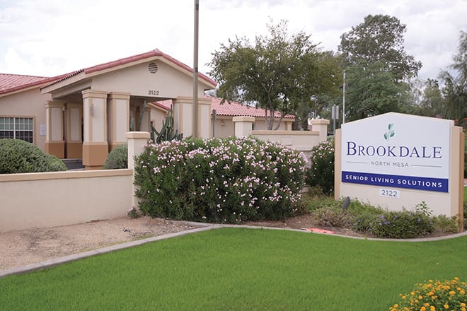 A residential building with a sign and landscaped garden in front.