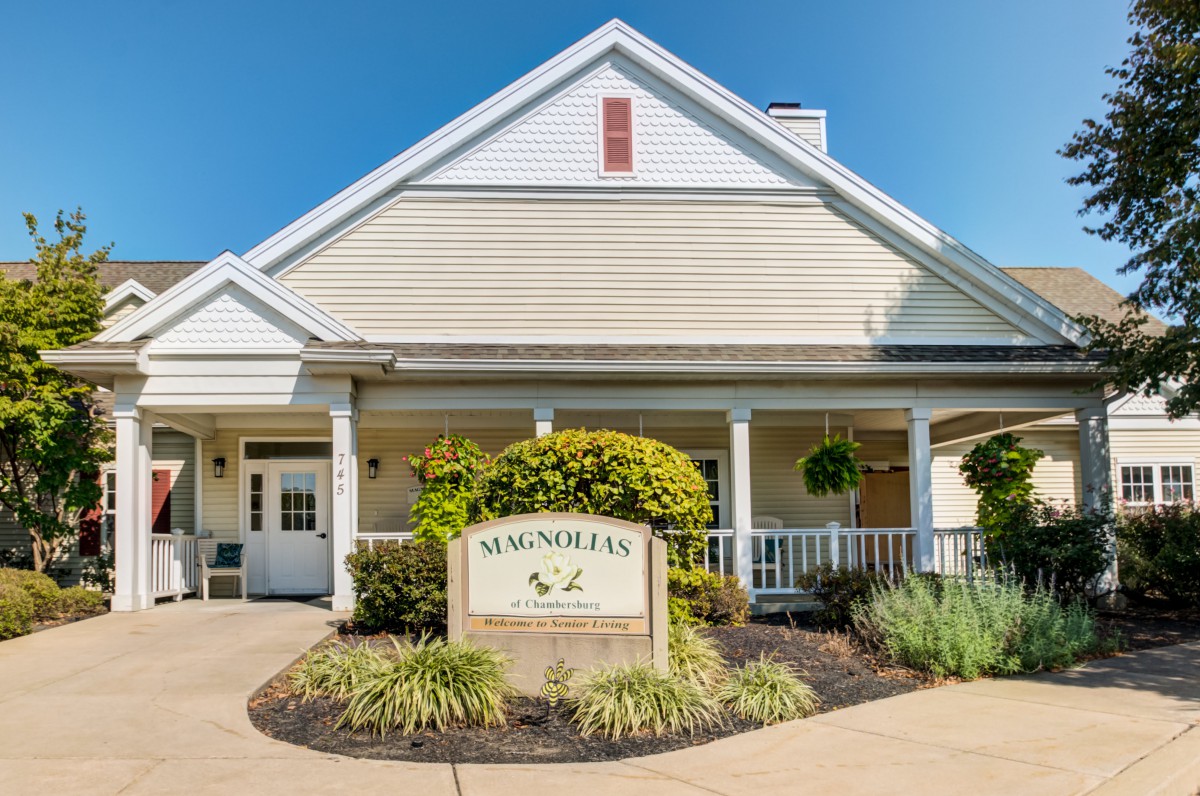 A residential building with a community sign at the entrance, surrounded by well-maintained landscaping.