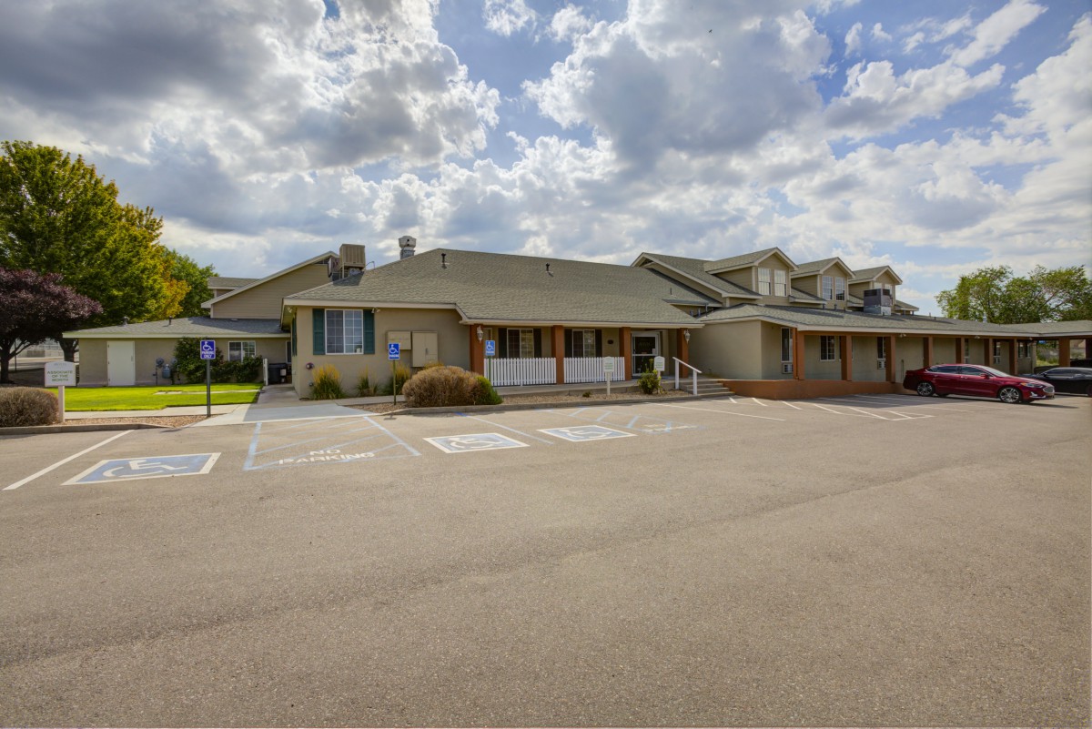 A residential building with an adjacent parking lot under a cloudy sky.