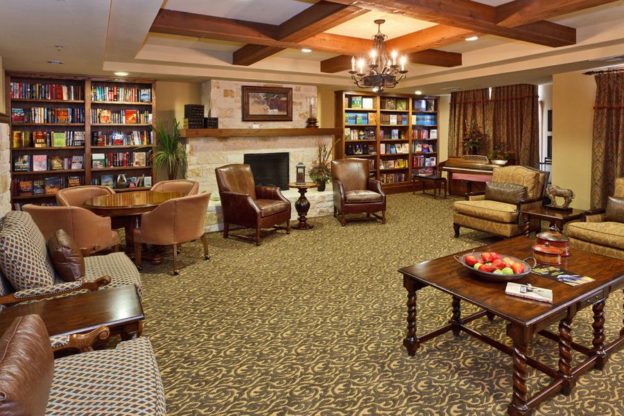 A cozy library room with comfortable seating, a fireplace, and well-stocked bookshelves.