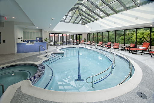 A serene indoor swimming pool featuring a glass ceiling and comfortable lounge chairs, perfect for relaxation.
