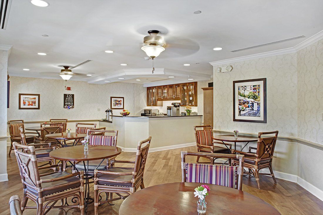 A cozy dining area with tables and chairs, featuring ceiling fans and warm lighting.