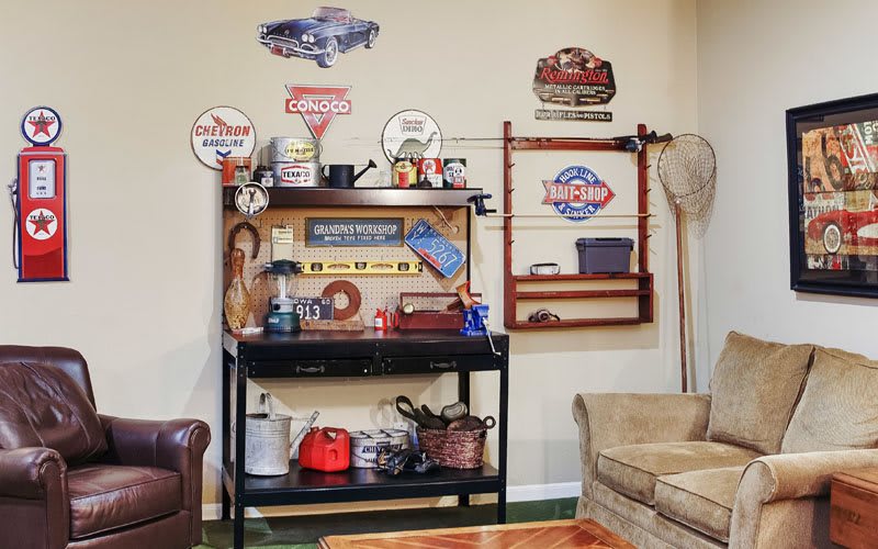 A cozy room decorated with vintage signs and memorabilia, featuring a shelf filled with various items and a fishing net on the wall.