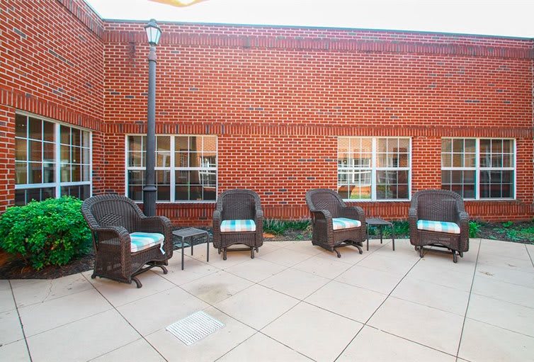 Outdoor patio with wicker chairs and a brick wall backdrop.