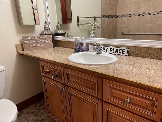 A bathroom with a wooden cabinet, sink, and decorative signs on the countertop.