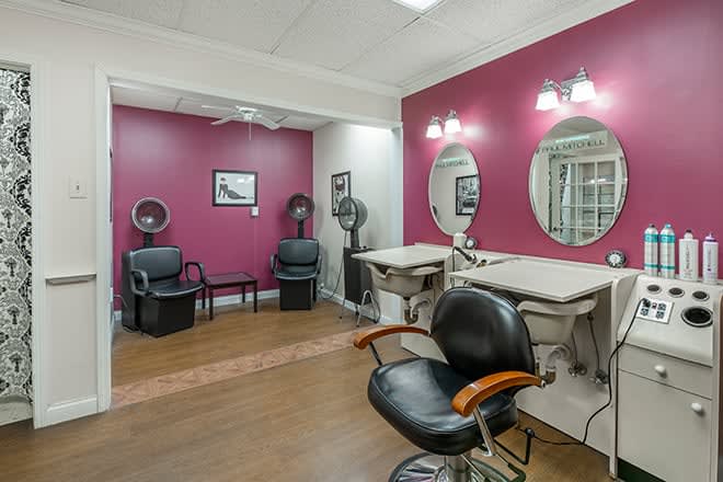 A well-organized hair salon interior featuring styling chairs, mirrors, and vibrant wall colors.