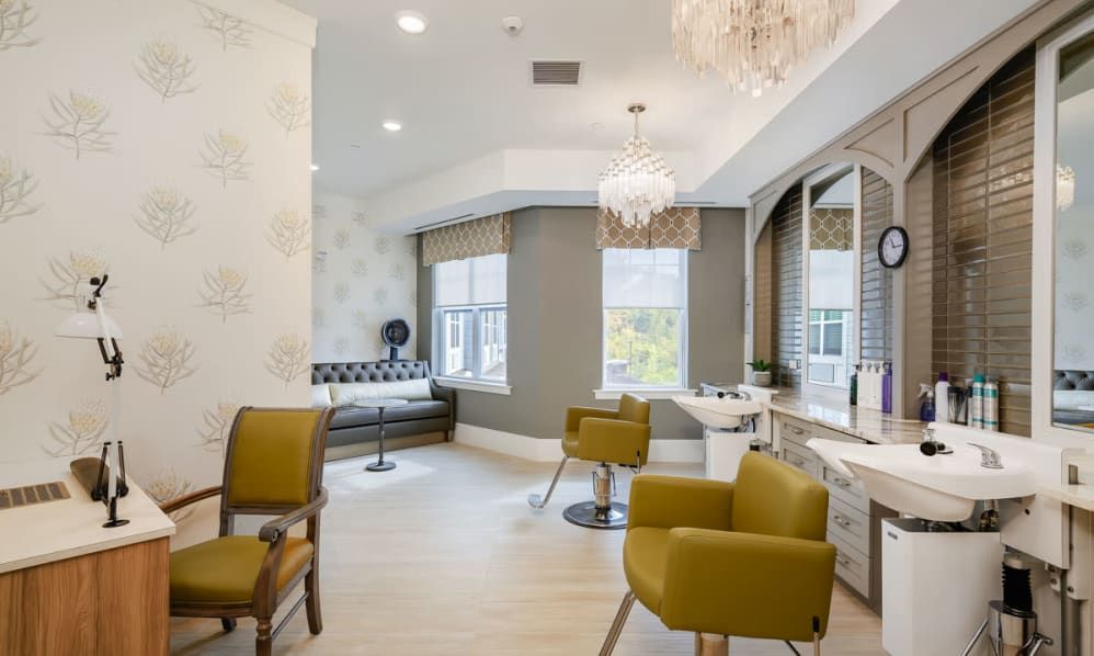 A modern salon interior with stylish seating, large mirrors, and elegant chandeliers.