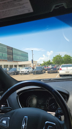 A view of a busy parking lot with various cars parked outside a modern building.