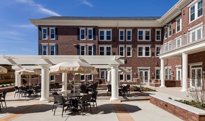 A brick building with a patio featuring outdoor seating and decorative columns.