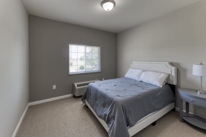 A minimalist bedroom with gray walls and a neatly made bed.