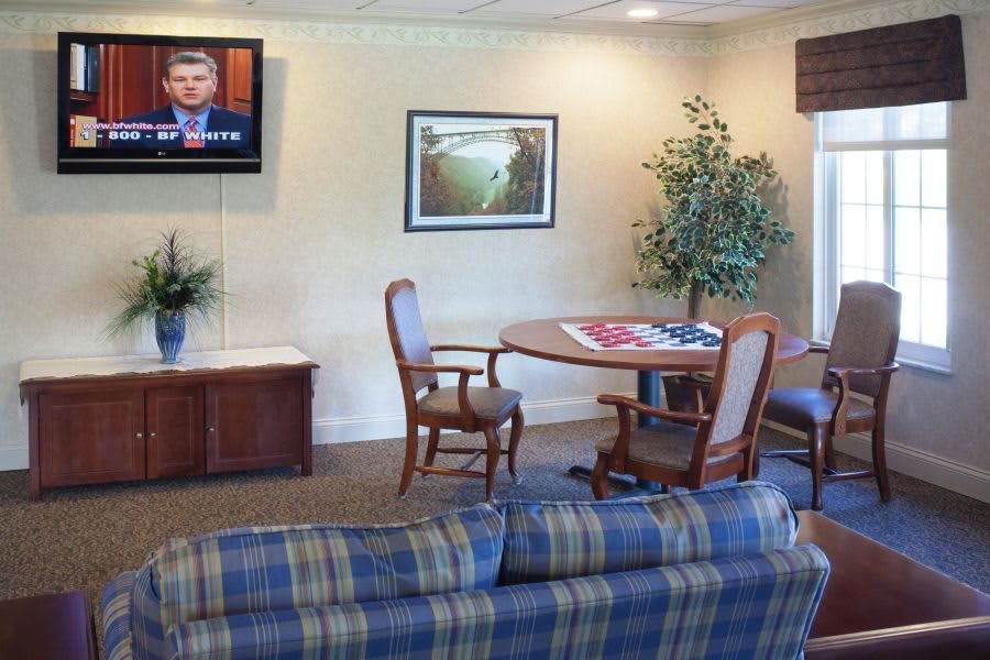 A cozy living room setup featuring a television, table with chairs, sofa, and indoor plant.