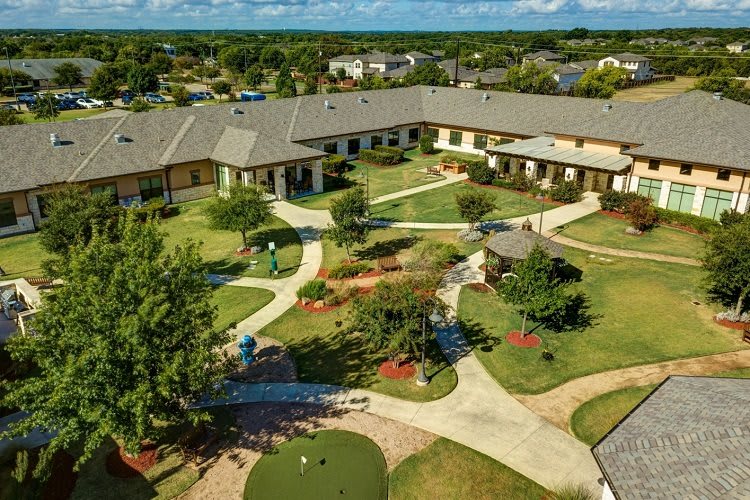 Aerial view of a landscaped residential complex with pathways and gardens.