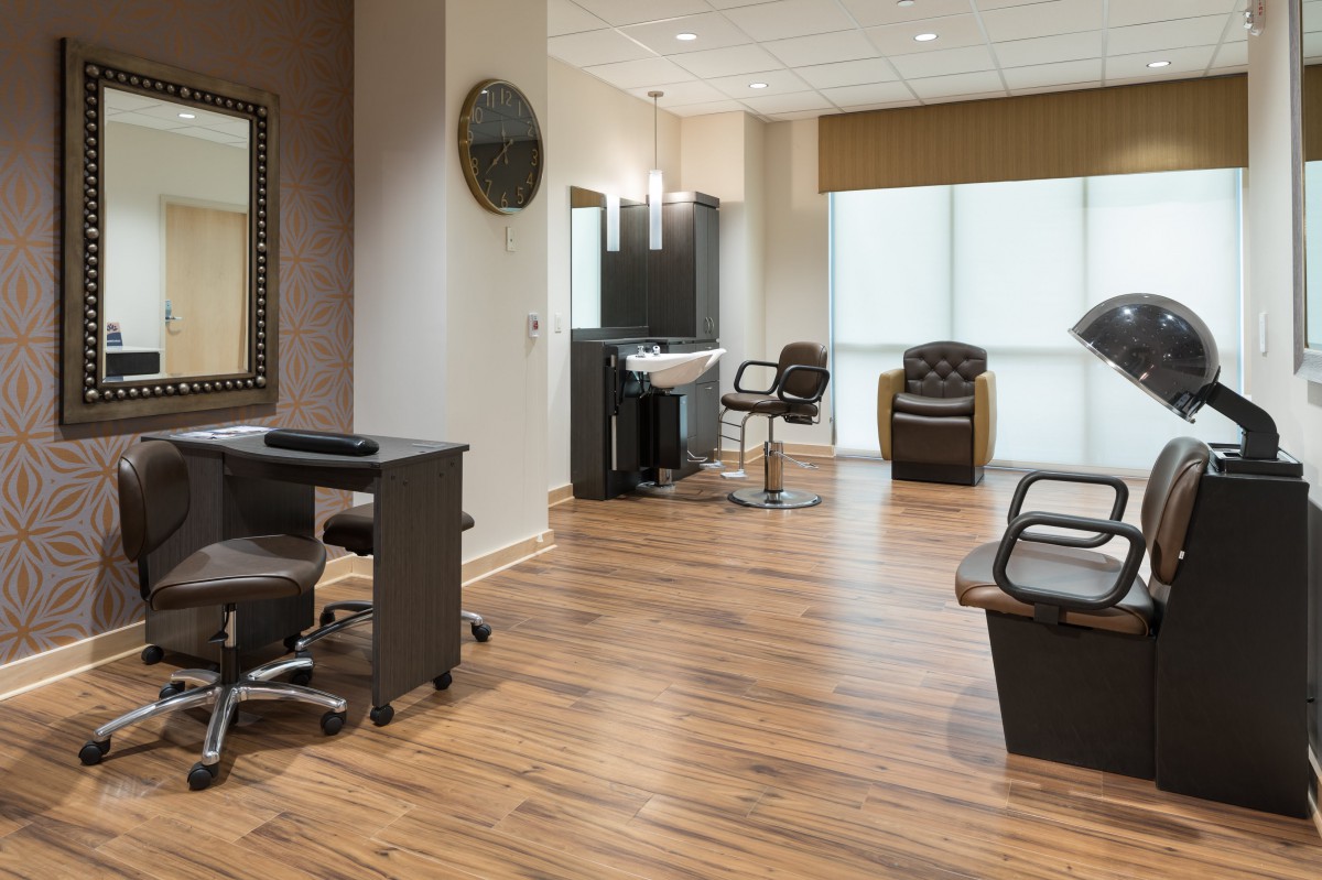 A modern hair salon interior with wooden flooring, mirrors, and styling chairs.