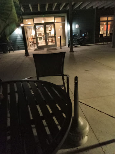A quiet outdoor seating area at night, featuring empty chairs and a table.
