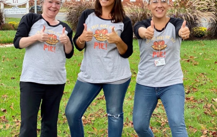 Three people standing outdoors giving thumbs up.