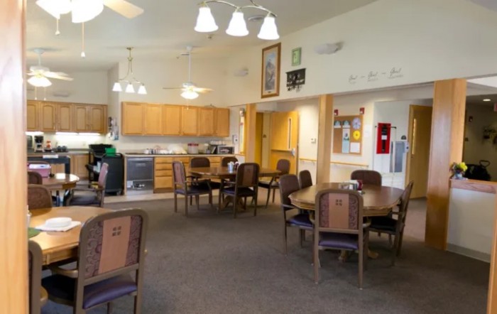 A communal dining area with several tables and chairs, adjacent to a small kitchen.