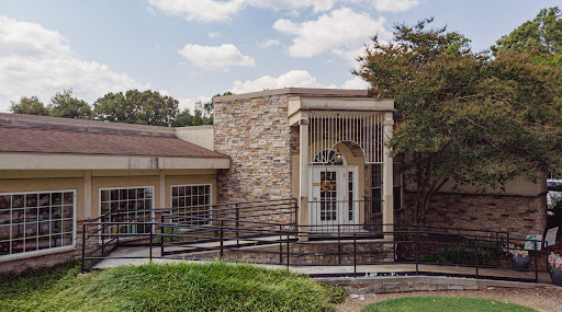 A modern stone-faced building with a ramp and an inviting entrance.