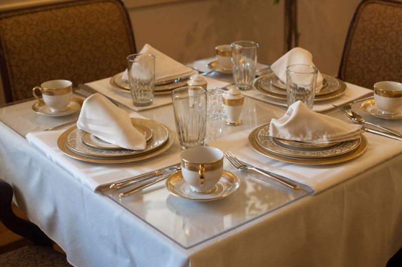 A formal dining table set with elegant dinnerware and neatly folded napkins.